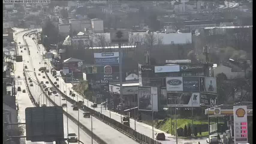 A highway with moderate traffic flows through a city on a sunny day.