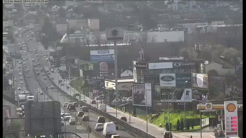 A highway with moderate traffic flows through a city on a sunny day.