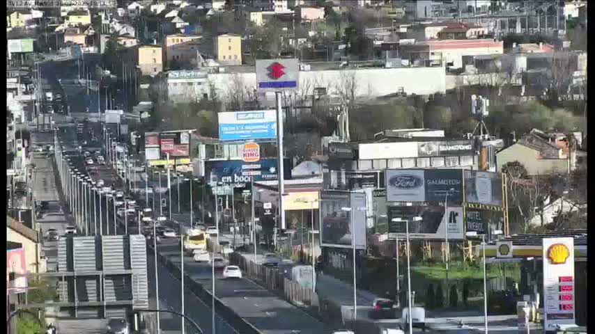 A long highway with moderate traffic flows through a city on a partly sunny day.