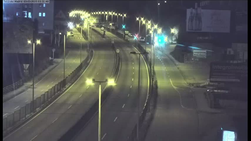 A nighttime view of a multi-lane highway with several vehicles driving on it, illuminated by streetlights.