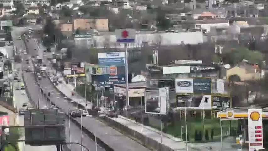 A highway with moderate traffic flows through a city on an overcast day.