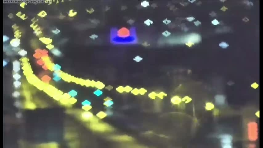 A blurry nighttime view of multicolored lights from traffic on a roadway, possibly in the rain.