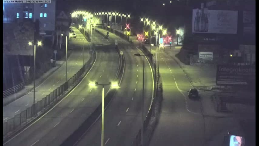 A nighttime view of a multi-lane highway with sparse traffic, illuminated by streetlights.