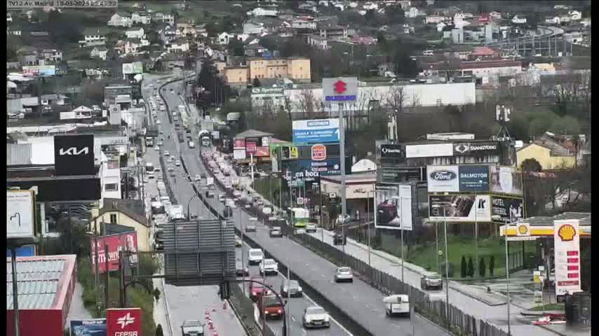 A multi-lane highway with heavy traffic flows through a city on an overcast day.