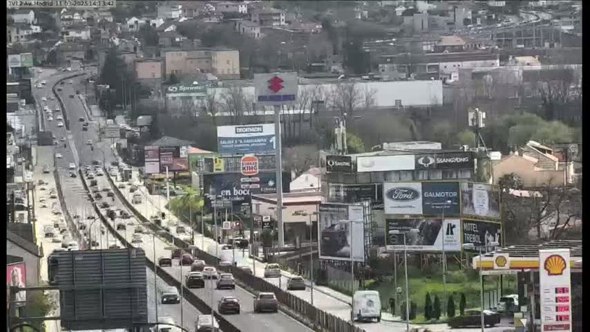 A highway with moderate traffic flows through a city on a partly sunny day.