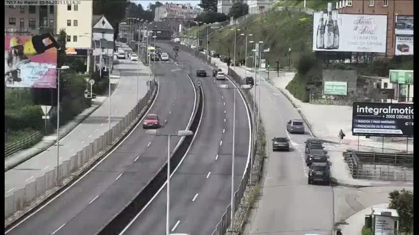 A multi-lane highway with several cars driving in both directions on a partly sunny day.