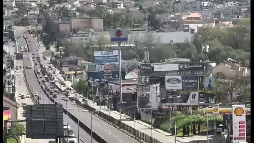 A highway with moderate traffic flows through a city on a partly cloudy day.