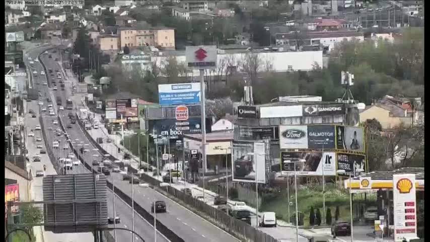 A highway with moderate traffic flows through a suburban area on an overcast day.