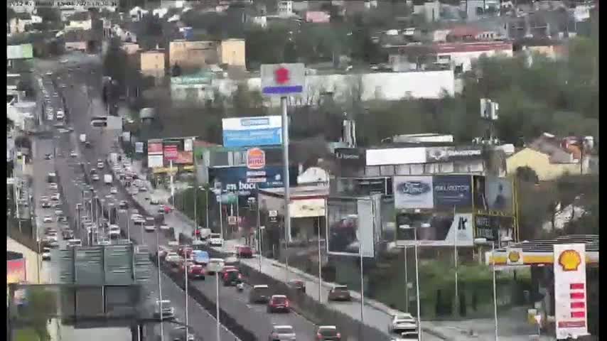 A highway with moderate traffic flows through a city on an overcast day.