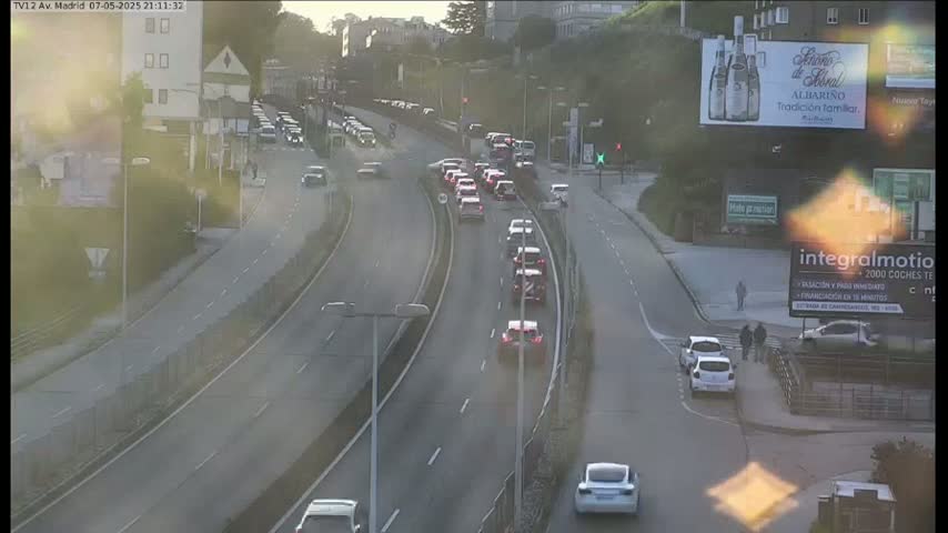 A highway with moderate traffic flows under a partly sunny sky, with several cars visible at an intersection.