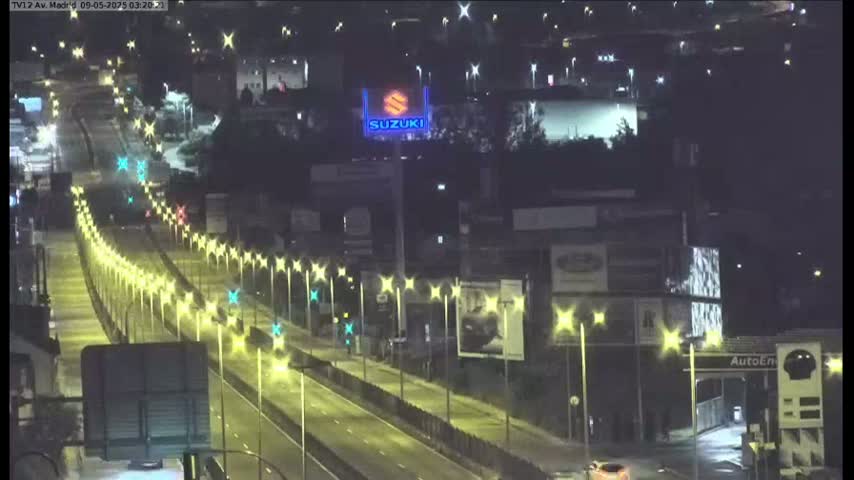 A brightly lit highway at night curves through a city, lined with streetlights and billboards.