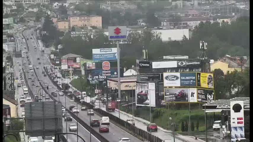 A busy highway with moderate traffic flows through a city under an overcast sky.