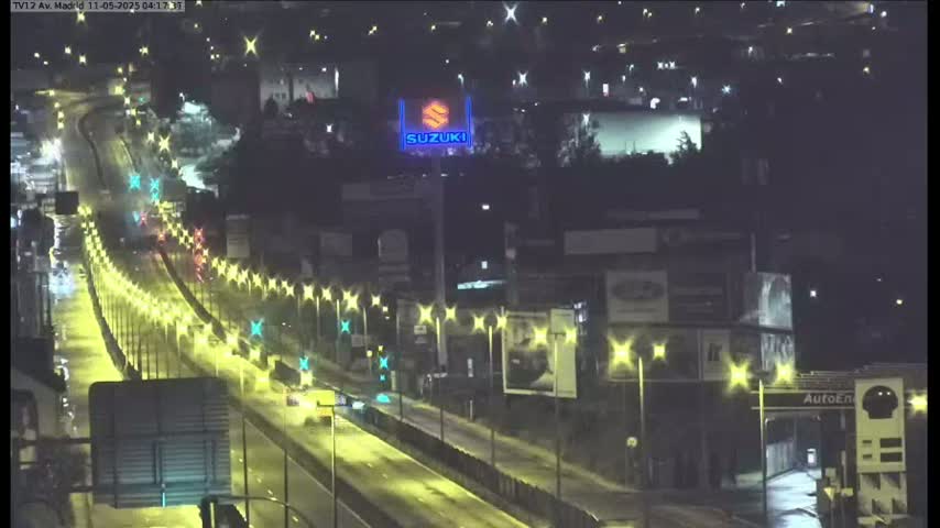 A nighttime, brightly lit highway scene shows moderate traffic flowing under a Suzuki sign; the road is lined with lights.