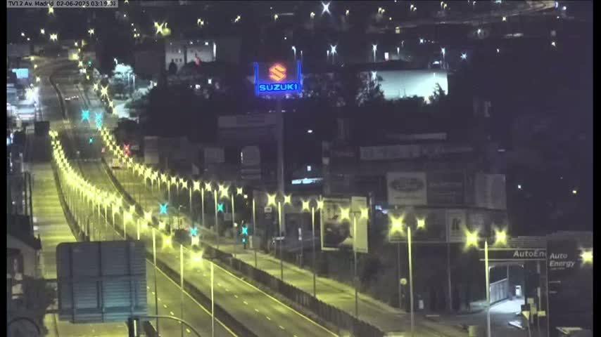 A nighttime view of a multi-lane highway illuminated by streetlights, with a Suzuki sign visible in the background.