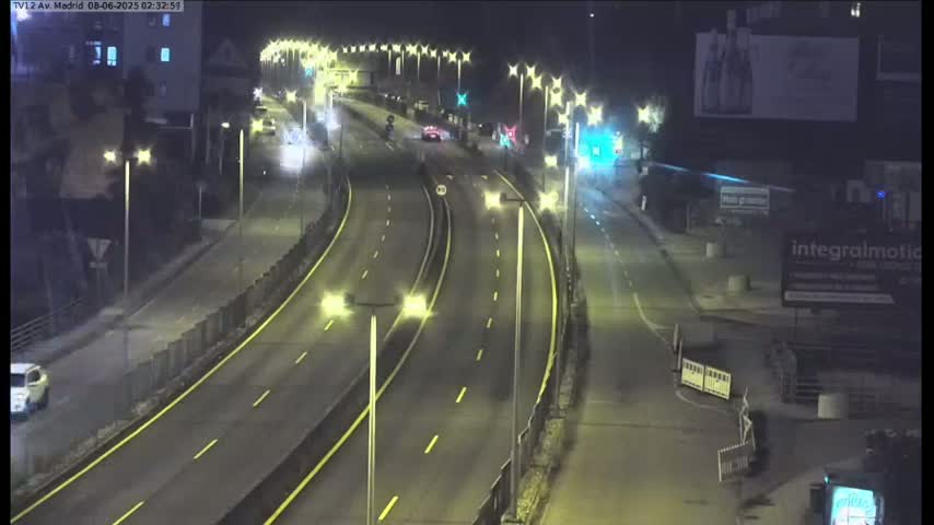 A nighttime view of a multi-lane highway with sparse traffic, illuminated by streetlights.