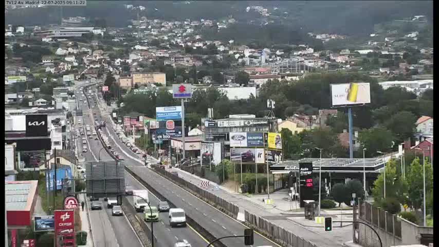 A highway with moderate traffic flows through a suburban area on an overcast day.