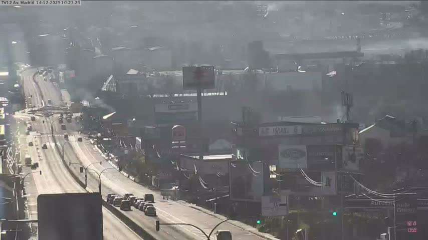 A wet urban highway at night is illuminated by the red taillights and white headlights of heavy traffic, with city lights visible in the background.