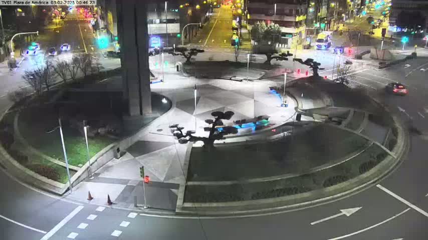 A nighttime aerial view of a circular plaza with geometric patterns, illuminated landscaping, and minimal vehicle traffic on surrounding roads.