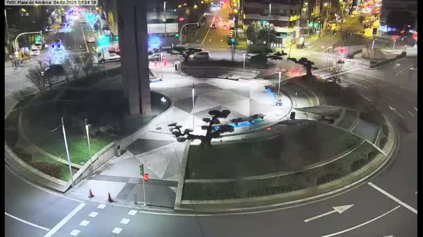 A nighttime aerial view of a circular roadway and plaza with landscaping features, illuminated by artificial lights.