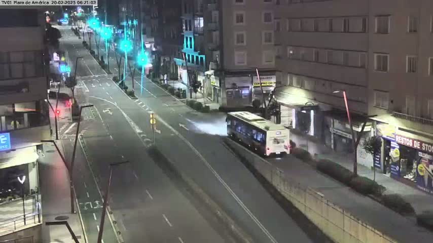 A bus drives down a city street at night, leaving a trail of what appears to be steam or exhaust.