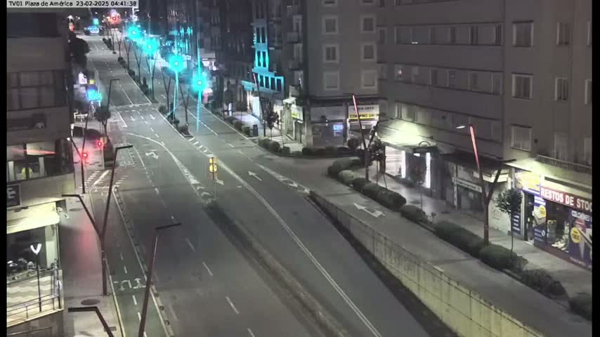 A mostly empty, well-lit street at night, lined with buildings, under clear skies.