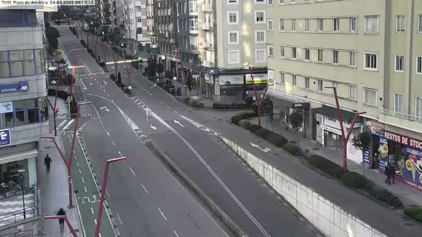 A mostly empty city street with buildings on either side, under a mostly clear sky.