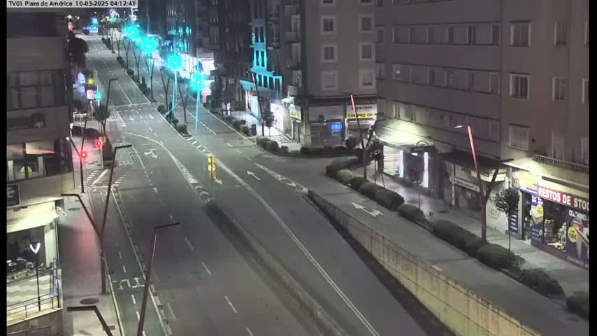 A mostly empty, brightly lit street at night, with buildings lining both sides.