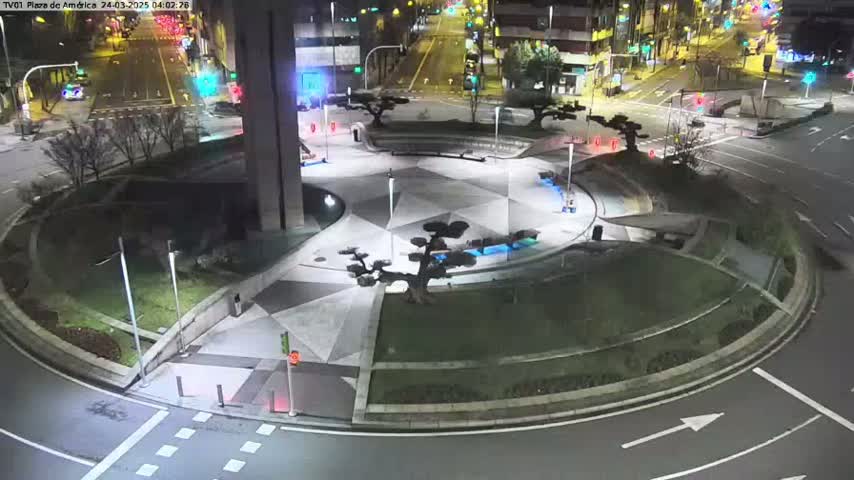 A nighttime aerial view of a circular plaza with landscaped areas, geometric pavement designs, and surrounding roadways.