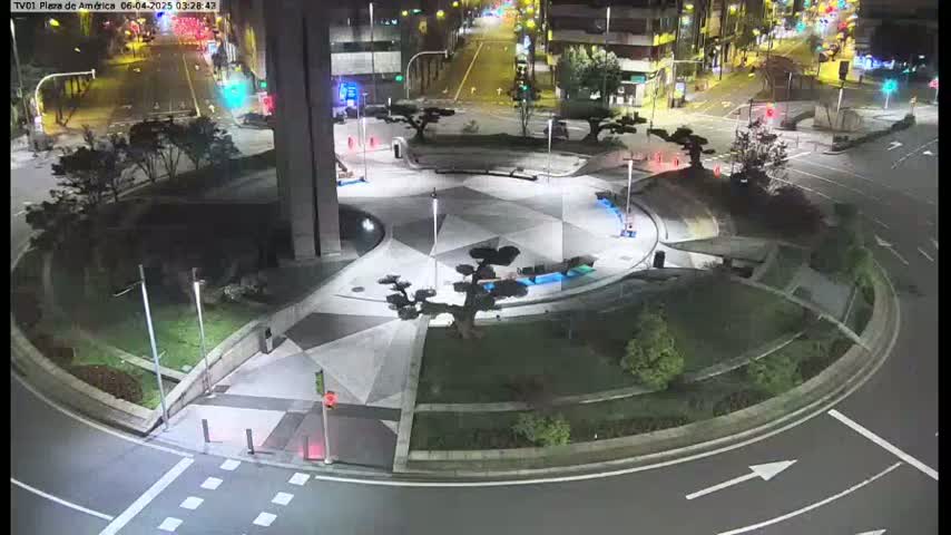 A nighttime aerial view of a circular plaza with geometrically patterned pavement, illuminated by streetlights, surrounded by roadways and landscaping.