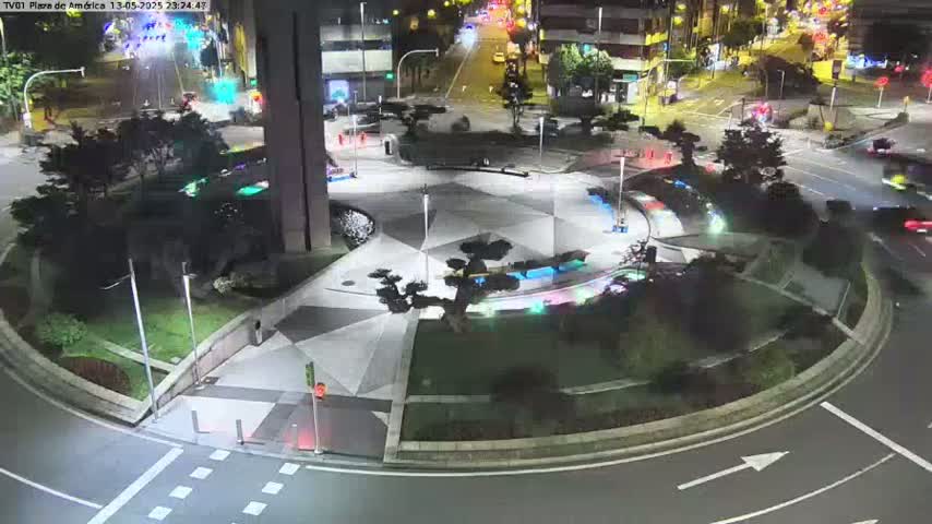 A nighttime aerial view of a circular plaza with geometric patterned pavement, landscaping, and surrounding roadways with sparse traffic.