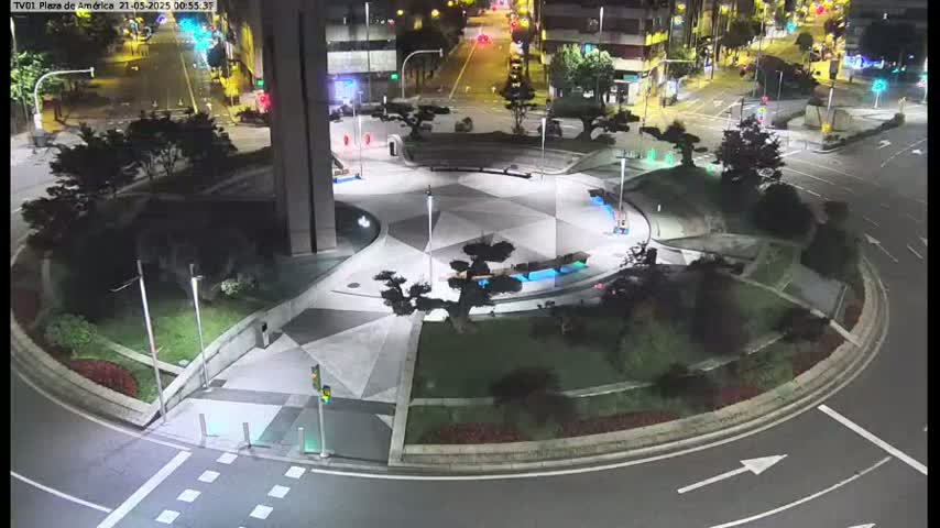A nighttime aerial view of a landscaped roundabout with geometric pavement designs, surrounded by roadways and streetlights.