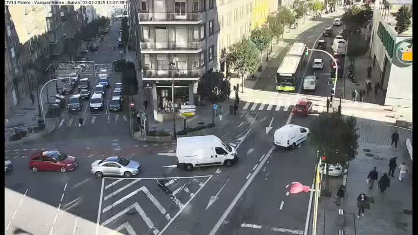 A high-angle view of a city intersection with numerous cars and a bus, under a sunny sky.