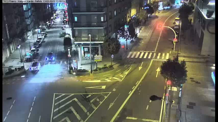 A nighttime high-angle view of a city intersection with several cars and a bus, illuminated by streetlights.