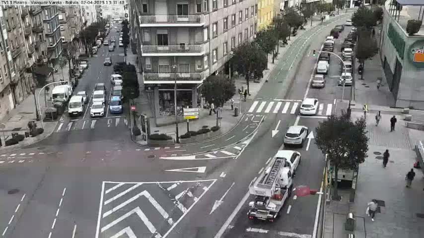 A city street intersection with several cars and pedestrians, a firetruck at a stop, and a partly sunny day.