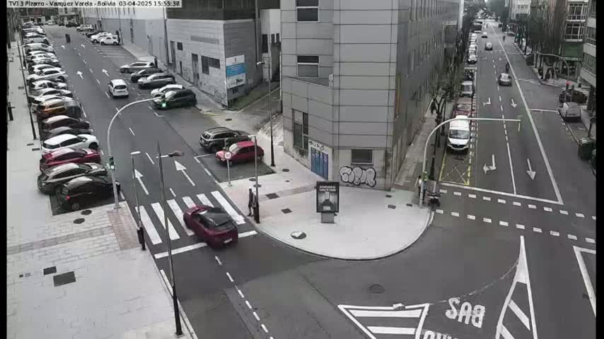 A street intersection with parked and moving cars on a partly cloudy day.