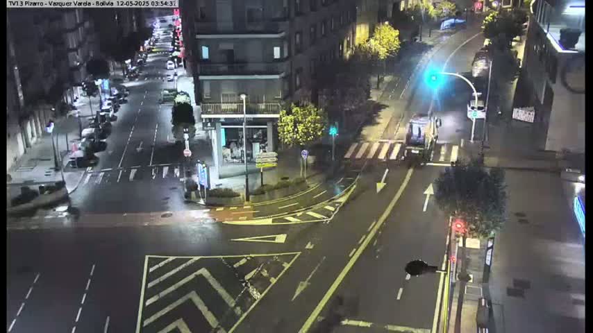 A wet, nighttime street intersection shows several cars and buildings under streetlights.