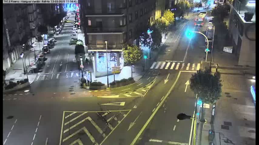A nighttime, overhead view of a city intersection with several cars and buildings visible under dark, well-lit conditions.