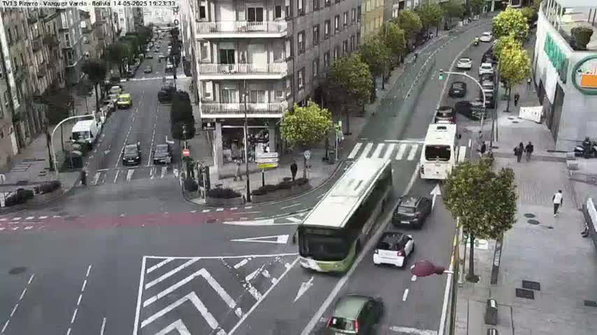 A high-angle view of a city intersection with several cars and buses on a sunny day.