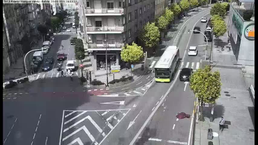 A city street intersection with several cars and a bus, under a sunny sky.