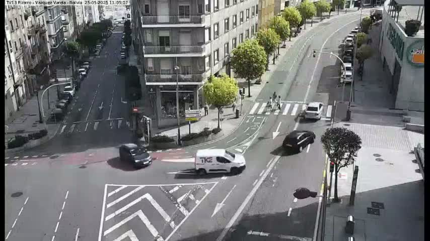 A street intersection with several cars and a van, viewed from above on a sunny day.