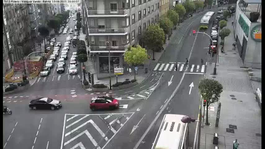 A city street intersection with several cars and a bus, viewed from above on an overcast day.