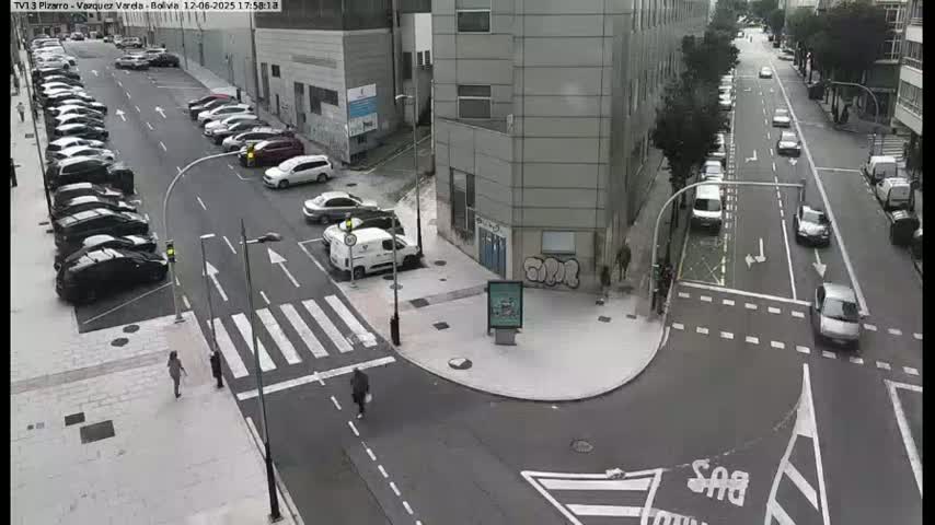 A street intersection with parked and moving cars on a partly cloudy day.