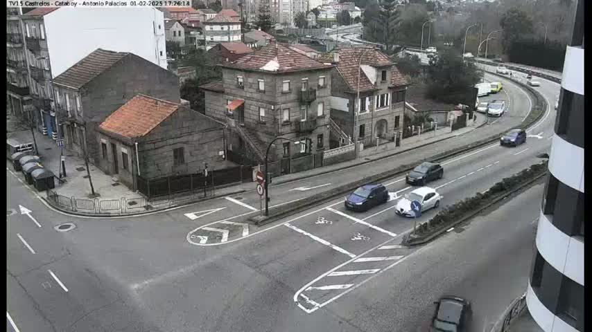 A street intersection with several cars and stone buildings is visible on an overcast day.