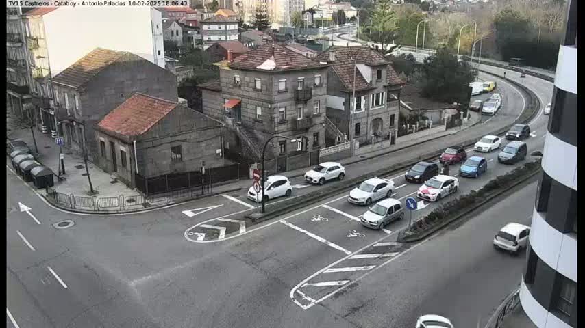 A street intersection with several cars and buildings, on an overcast day.