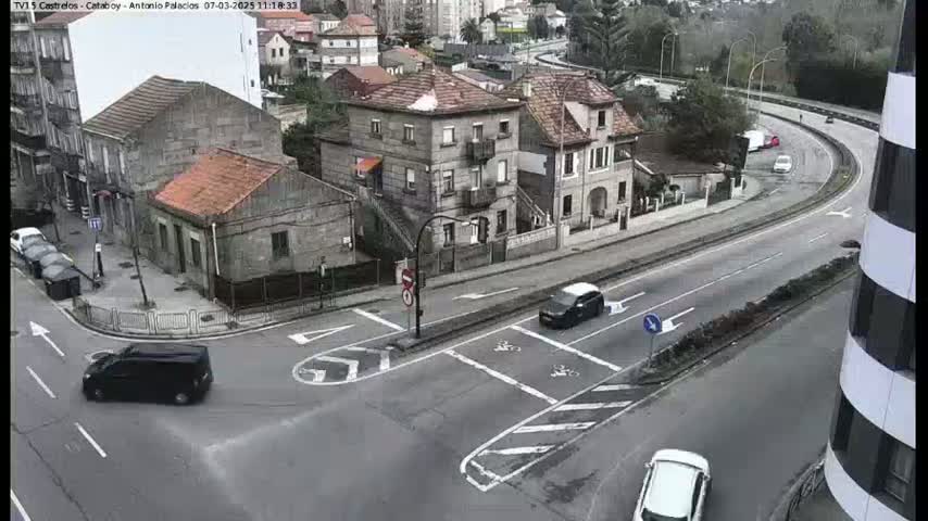 A street intersection with several buildings, some cars, and overcast skies.