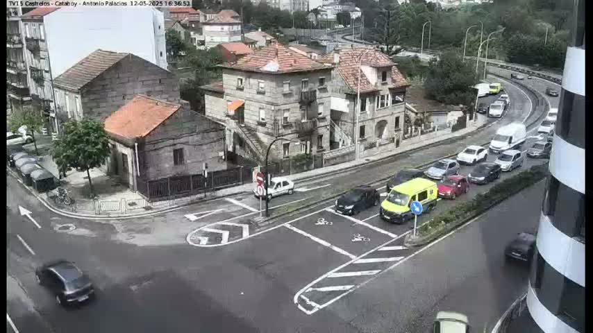 A street intersection with several cars and buildings, on an overcast day.