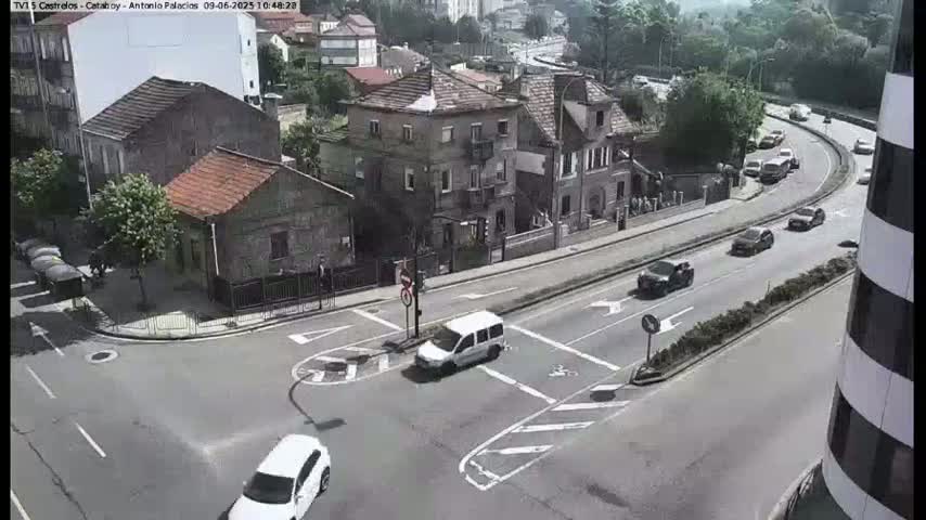 A street intersection in a residential area with several cars driving on a sunny day.