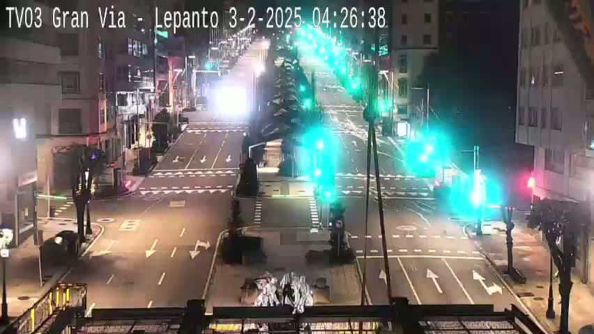 A nighttime, city street intersection with traffic lights and sparse vehicle traffic.