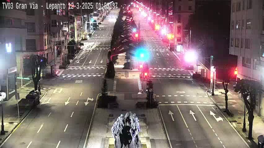 A nighttime, high-angle view of a city intersection with traffic lights and a statue in the center, illuminated by streetlights.