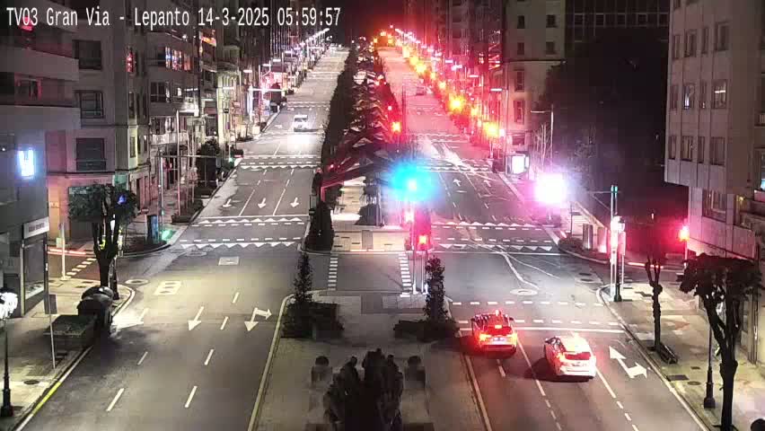 A nighttime, city street intersection with several vehicles and traffic signals, under clear skies.